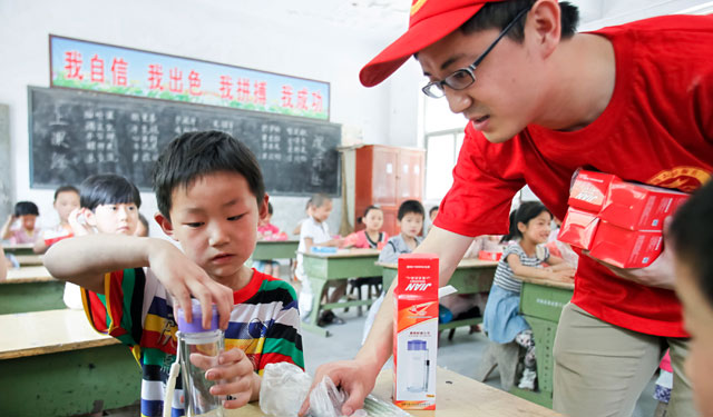 图为5月29日，国网滑县供电公司的青年志愿者在桑村乡齐邱村小学1年级1班正在给孩子们发放图书文具和安全用电宣传画。