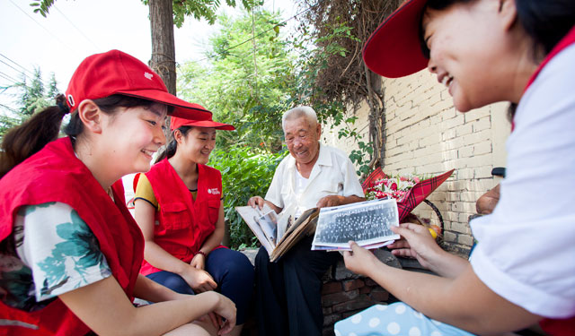 图4为7月1日国网滑县供电公司“小红帽”青年志愿者陪老党员翻看老照片。