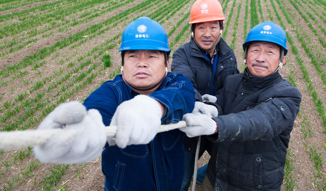 图2为11月17日，河南滑县牛屯镇10千伏牛街线路42号杆处施工现场，3名滑县供电公司员工正在麦田里紧固拉线。