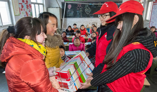 图为1月21日，河南滑县革命老区桑村乡齐邱中心小学三年级一班，国网滑县供电公司‘小红帽’青年志愿者向孩子们赠送图书。