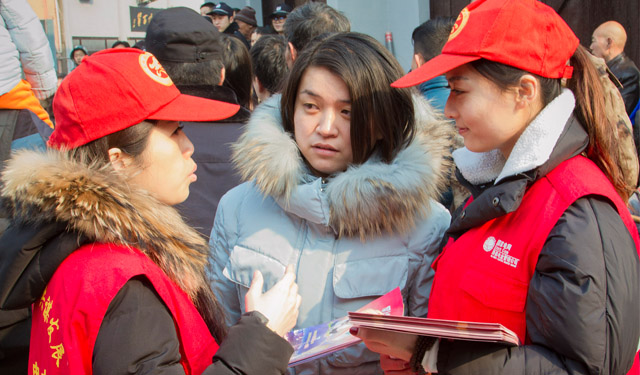 图为2月5日，河南滑县道口古镇街区，国网滑县供电公司两名电力小红帽志愿者正在为游客宣讲用电常识和掌上电力APP。