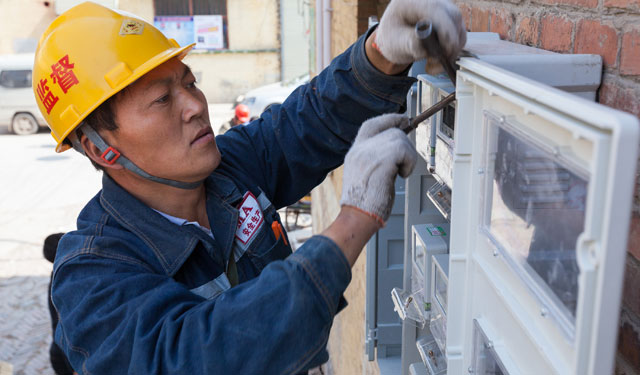 图为4月20日，河南滑县道口镇教育路，电力施工人员正在进行智能电表配套升级改造工作安装表箱。