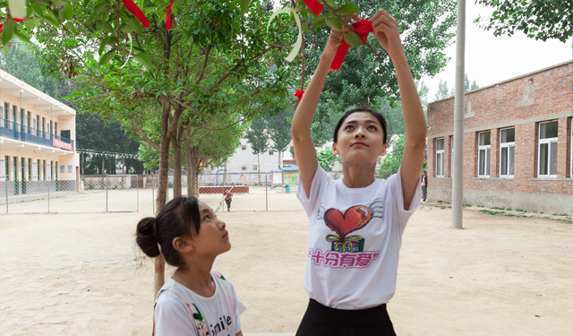 图为6月3日，国网滑县供电公司组织青年志愿者，在该县瓦岗赤水小学“十分有爱”童书馆前和孩子们一起许心愿。