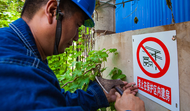 线路附近有施工建房或施工的，在其附近醒目处张贴电力线路安全小知识及事故典型案例，对施工中施工人员每人签订《电力安全宣传告知书》，并在所建房屋附近电杆悬挂安全警示牌；图为2016年8月10日，国网滑县供电公司工作人员正在安装供电设施保护区域标识牌。