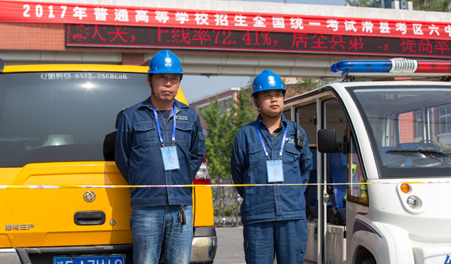 图为6月7日，考点门口的电力员工在高温下侍命。