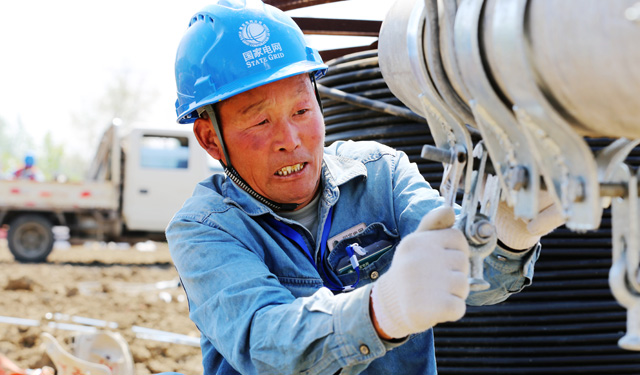 农村电气化网讯：4月17日上午，在安徽省利辛县程家集镇王宣庄，国网利辛县供电公司外线施工员工正在组立10千伏程集105线王宣庄台区15米电杆并架设高压绝缘线。