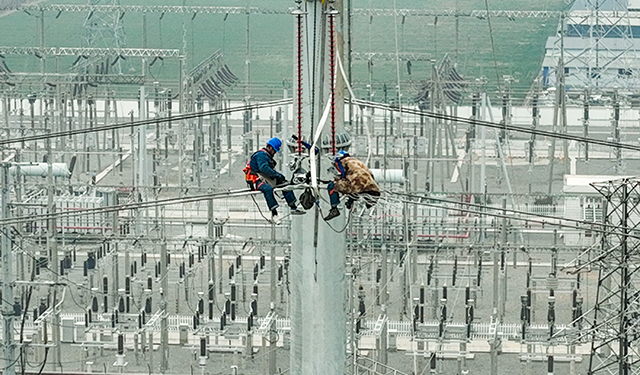 图为2月27日，在河南滑县新濮路中段的220千伏高压线路上，电力施工人员正在60米高的铁塔上紧固导线，确保本次迁改工程的有序完成，为地方经济社会高质量发展提供了坚实保障。