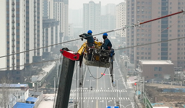 图为2月27日，在河南滑县新濮路中段的220千伏高压线路上，电力施工人员正在60米高的铁塔上紧固导线，确保本次迁改工程的有序完成，为地方经济社会高质量发展提供了坚实保障。